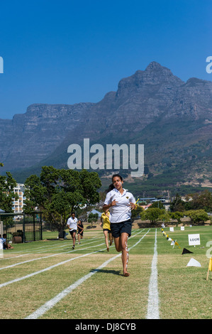 Fille courir en bas de la voie aux champs sports le jour, l'école St Georges, Cape Town, Afrique du Sud Banque D'Images