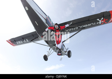 Ce garçon parachutiste a attaché un conseil sur ses pieds et saute d'un avion. Il s'amuse à surfer sur le ciel. Banque D'Images