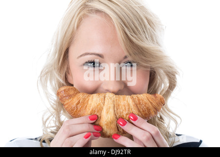 Happy attractive Smiling Young Woman Holding et de manger un petit-déjeuner continental de style français de boulangerie croissant sur un fond blanc. Banque D'Images