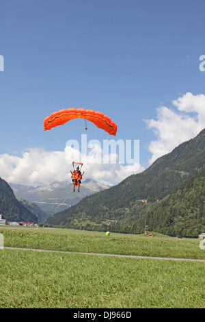 Parachutiste sous voile s'approche de la zone d'atterrissage après une skydive jump dans entre les montagnes. Banque D'Images