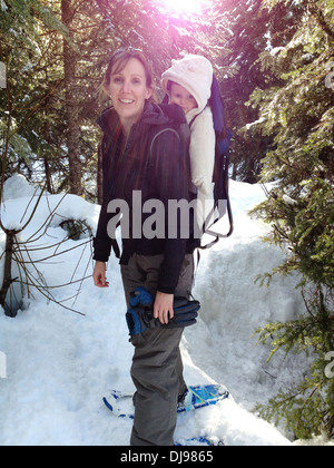 Caucasian mother carrying baby in Snowy Woods Banque D'Images