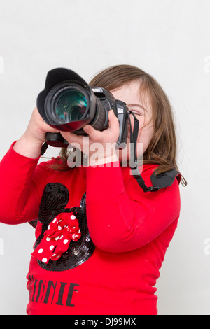 Jeune fille avec le syndrome de Down posant avec un appareil photo Canon 20D sur un fond blanc. Banque D'Images