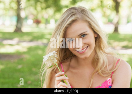 Portrait de jolie jeune femme montrant une fleur blanche Banque D'Images