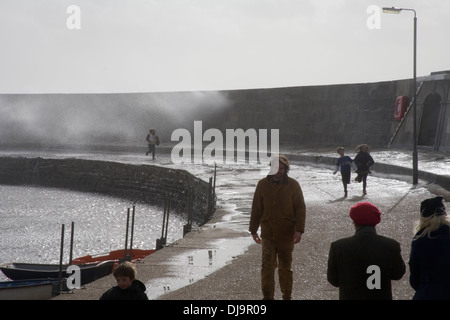 Personnes le long mur du port comme les vagues déferlent sur la paroi de la mer dans la tempête Banque D'Images