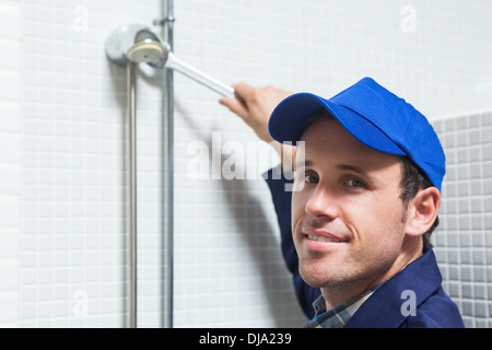 Cheerful plumber repairing douche head Banque D'Images