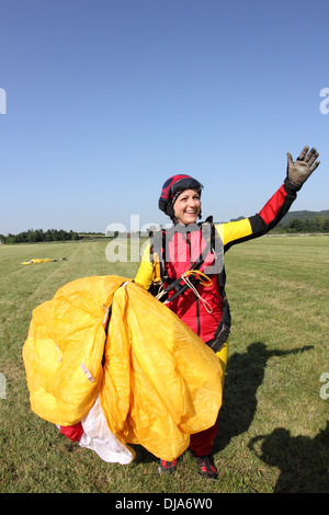 Cette fille débarque avec son parachutiste parachute et est maintenant très heureux d'être enregistrer sur le sol. Banque D'Images