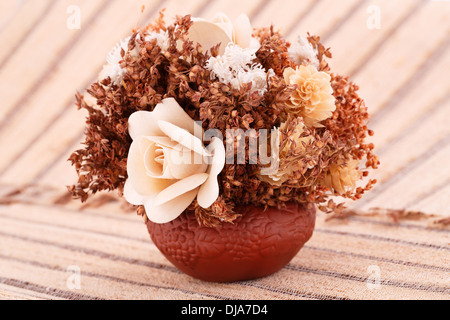 Fleurs dans vase isolé sur fond de nattes de bambou. Banque D'Images