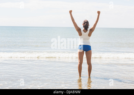 Belle slim woman standing on beach raising her arms Banque D'Images