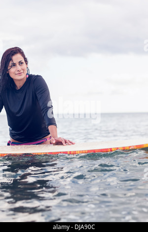Belle jeune femme holding surfboard at Beach Banque D'Images