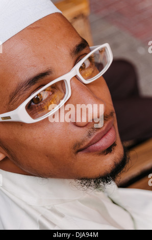 Un homme portant des vêtements traditionnels indiens et des lunettes est assise sur un banc à Deira. Dubaï, Émirats arabes unis. Banque D'Images