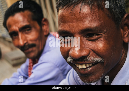 Deux travailleurs immigrés prennent une pause de leur travail dans les rues de Deira. Dubaï, Émirats arabes unis. Banque D'Images