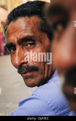 Deux travailleurs immigrés prennent une pause de leur travail dans les rues de Deira. Dubaï, Émirats arabes unis. Banque D'Images