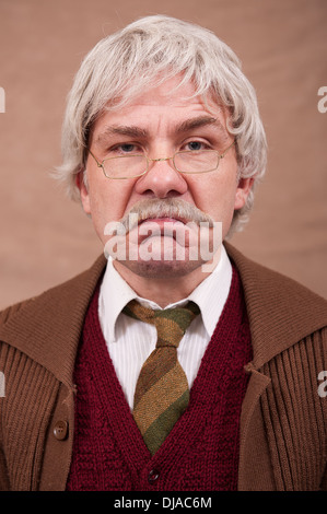 Portrait d'un vieil homme grincheux aux cheveux gris contre un fond brun. Banque D'Images