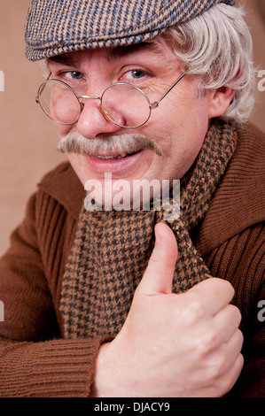 Vieil homme aux cheveux gris avec un grand sourire et un coup de pouce vers la caméra. Banque D'Images