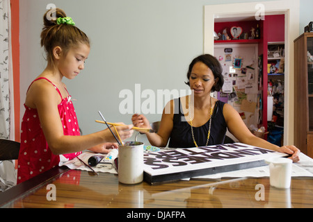 Mixed Race mother and daughter painting sign Banque D'Images