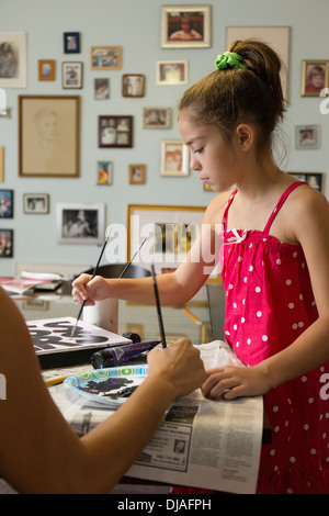 Mixed Race mother and daughter painting sign Banque D'Images