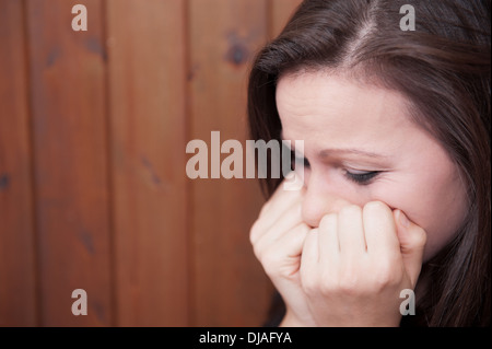 Jeune femme en colère avec son maquillage d'oeil fonctionnant en bas de son visage de larmes et sa tête dans ses mains. Banque D'Images