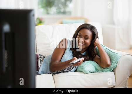 Black woman watching television on sofa Banque D'Images