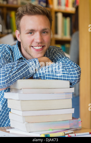 Male student avec pile de livres de bibliothèque Banque D'Images