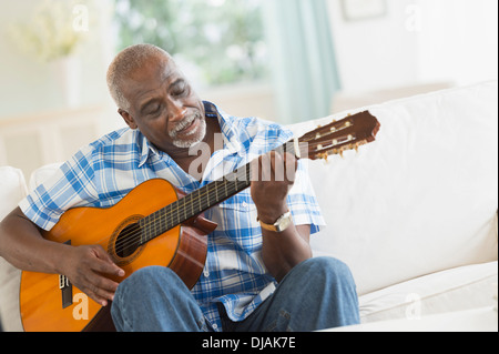 Black man playing guitar on sofa Banque D'Images