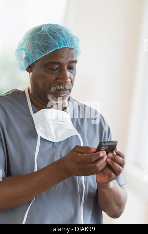 Chirurgien noir using cell phone Banque D'Images