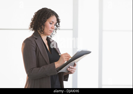 Hispanic businesswoman writing in office Banque D'Images