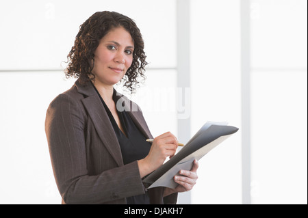 Hispanic businesswoman writing in office Banque D'Images