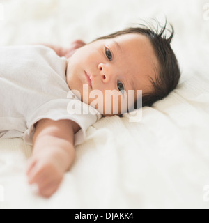 Hispanic baby laying on lit bébé Banque D'Images