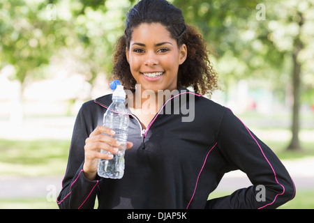 Portrait of a smiling woman with water bottle in park Banque D'Images