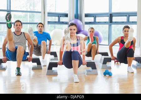 Avec l'instructeur fitness class performing step aerobics exercise Banque D'Images