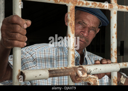 Un ancien prisonnier debout derrière une porte avec des barres de fer, l'ancien camp de concentration de Tarrafal ou Campo do Tarrafal, Tarrafal Banque D'Images