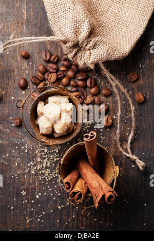 Les bâtons de cannelle, de sucre de canne et les grains de café sur fond de bois Banque D'Images