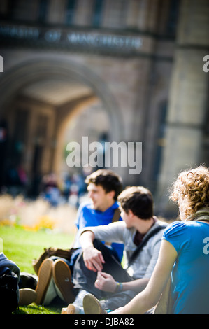 Groupe d'étudiants de l'université de Manchester raciale multi assis sur l'herbe sur le campus dans la région de Sunshine parler et rire à heureux Banque D'Images