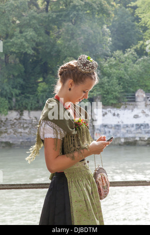 Germany, Bavaria, Munich, Oktoberfest Parade, jeune femme habillé en costume régional à l'aide d'iPhone Banque D'Images