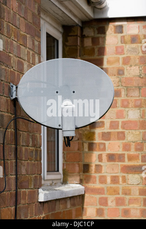 Plat satellite dish fixé sur le côté d'une chambre. Banque D'Images