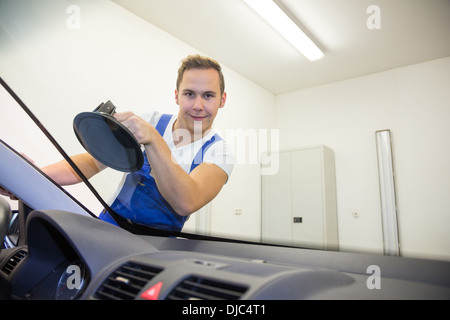 Glazier remplace pare-brise ou sur le pare-brise d'une voiture dans un garage atelier Banque D'Images