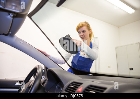 Glazier remplace pare-brise ou sur le pare-brise d'une voiture dans un garage atelier Banque D'Images