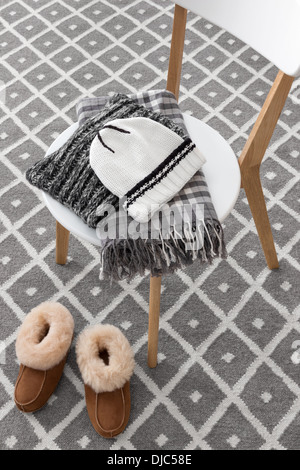 Chaussons chauds et des vêtements d'hiver sur une chaise. Banque D'Images
