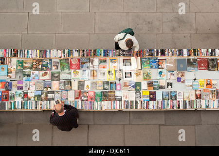 Vue de dessus de deux hommes parcourt second hand books sur une table, sur la rive sud de la rivière Thames à London. Banque D'Images