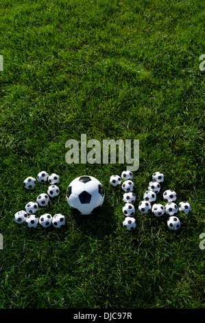 Message pour 2014 faite avec de petits ballons de football sur terrain de football en herbe verte Banque D'Images