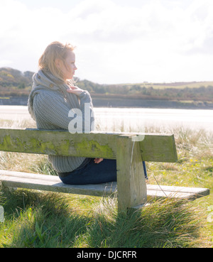 Jolie jeune femme assise sur un banc Banque D'Images