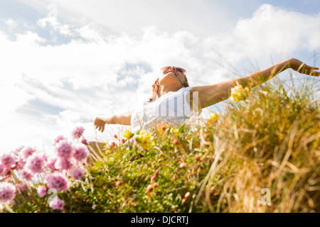 Femme se sentir libre dans le champ de fleurs sauvages Banque D'Images