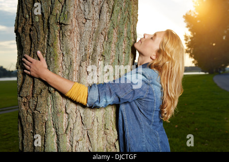 Allemagne, Berlin, young woman hugging tree Banque D'Images