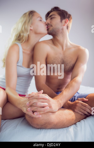 Sweet couple sitting on bed tenant la main et s'embrasser Banque D'Images