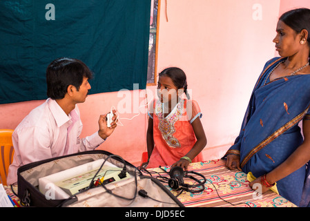 Deaf Indian village girl essayant d'une aide auditive à Sathya Sai Baba l'hôpital mobile. L'Andhra Pradesh, Inde Banque D'Images