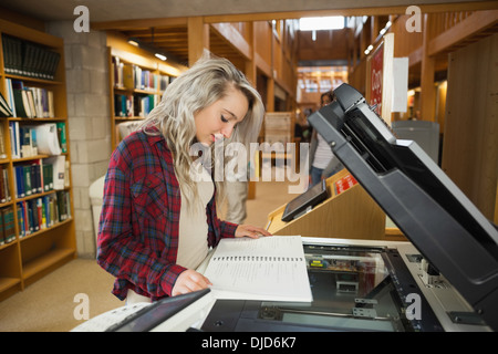 L'accent blonde debout à côté d'étudiants photocopieur Banque D'Images