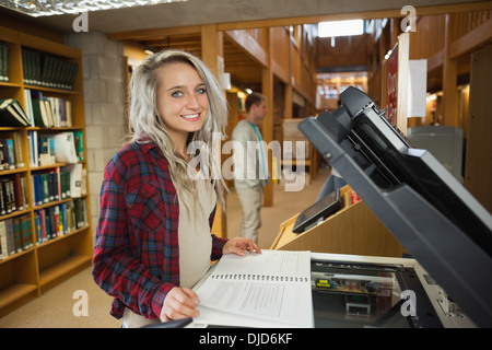 Cheerful blonde student standing à côté de photocopieur Banque D'Images