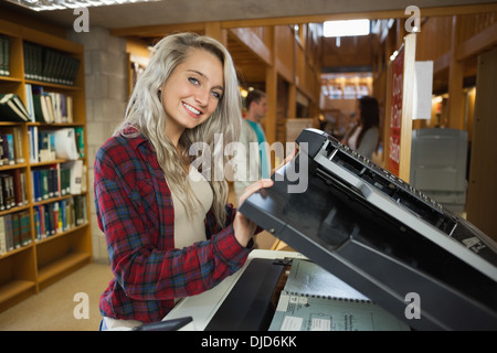 Cheerful blonde étudiant en utilisant un photocopieur Banque D'Images