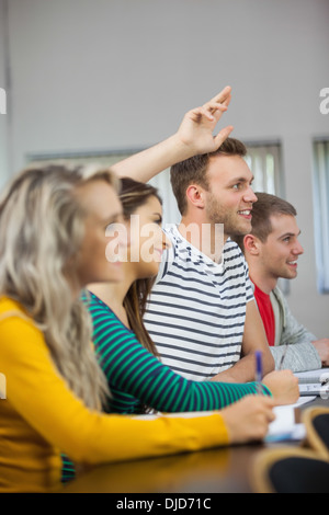 Handsome smiling student raising his arm Banque D'Images