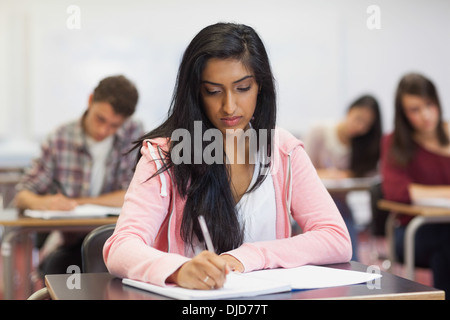 L'accent indian student taking notes in class Banque D'Images